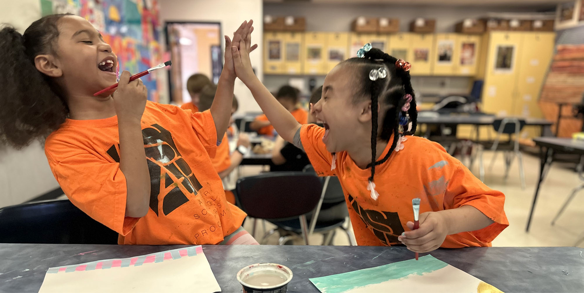 Two girls laughing and high fiving wearing ASAP shirts