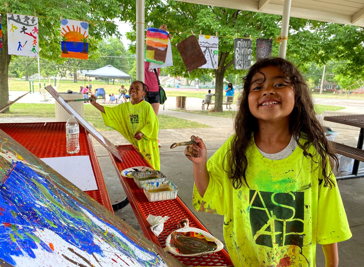 Two kids smiling and painting wearing yellow ASAP shirts